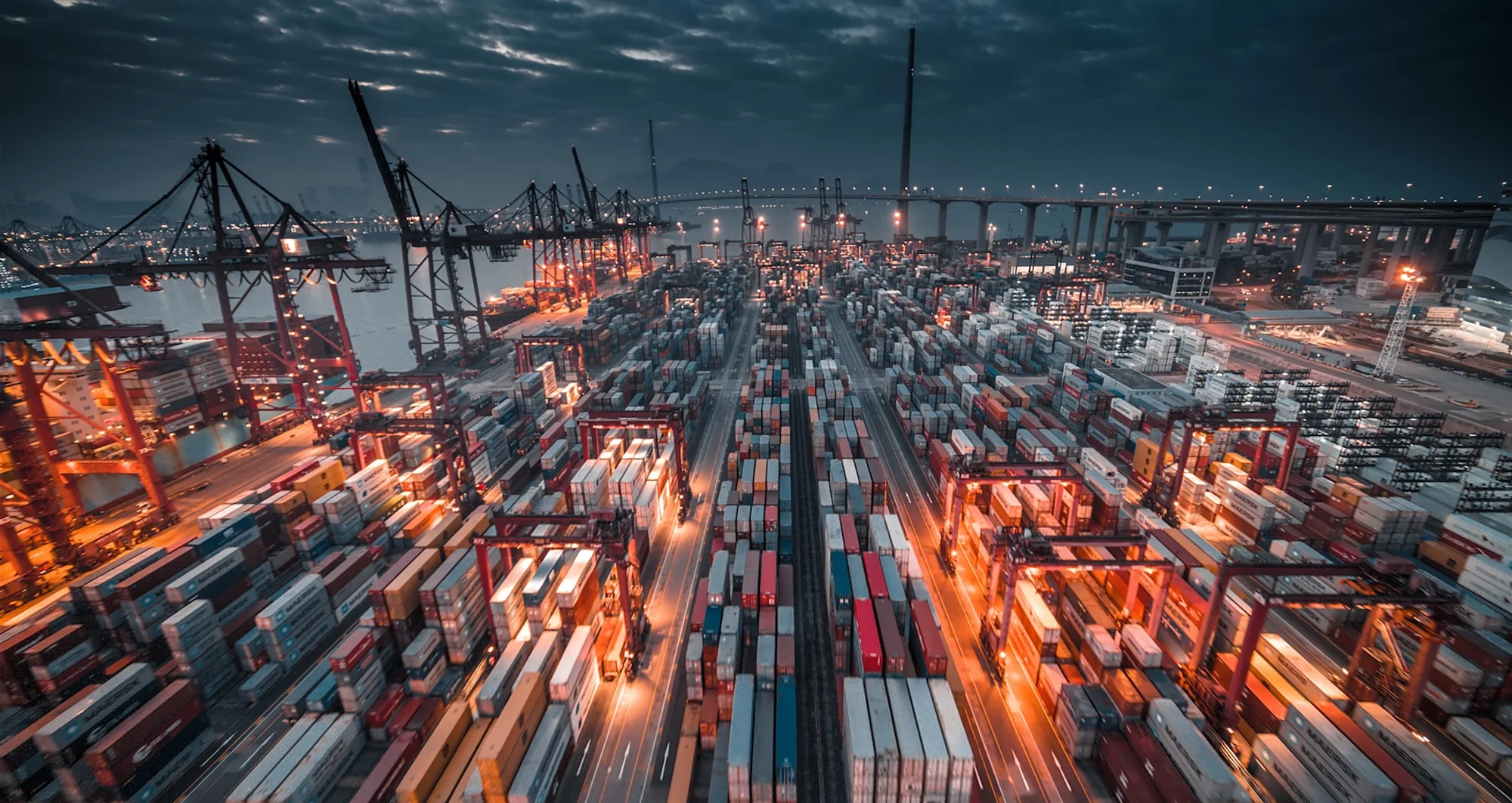 Terminal portuaria operando de noche con contenedores y grúas